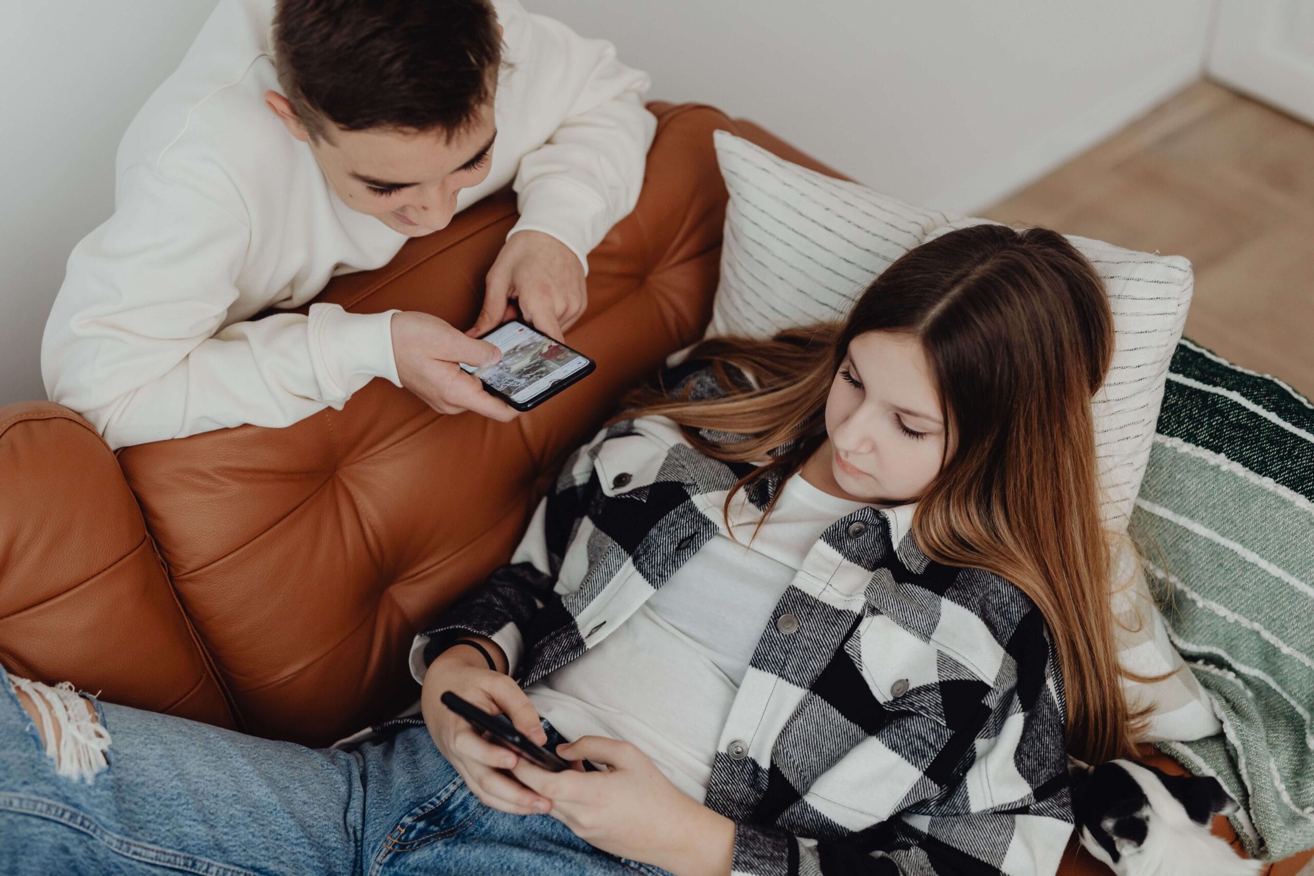 2 kinderen op de bank met hun telefoon